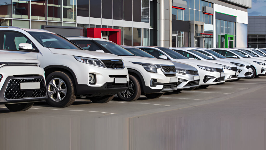 How to Choose a Reliable Car Rental in Albania (and Avoid Tourist Scams) 2 Line of white cars parked outside a modern car rental agency in Albania, showcasing a variety of vehicles available for tourists seeking a reliable car rental in Albania.