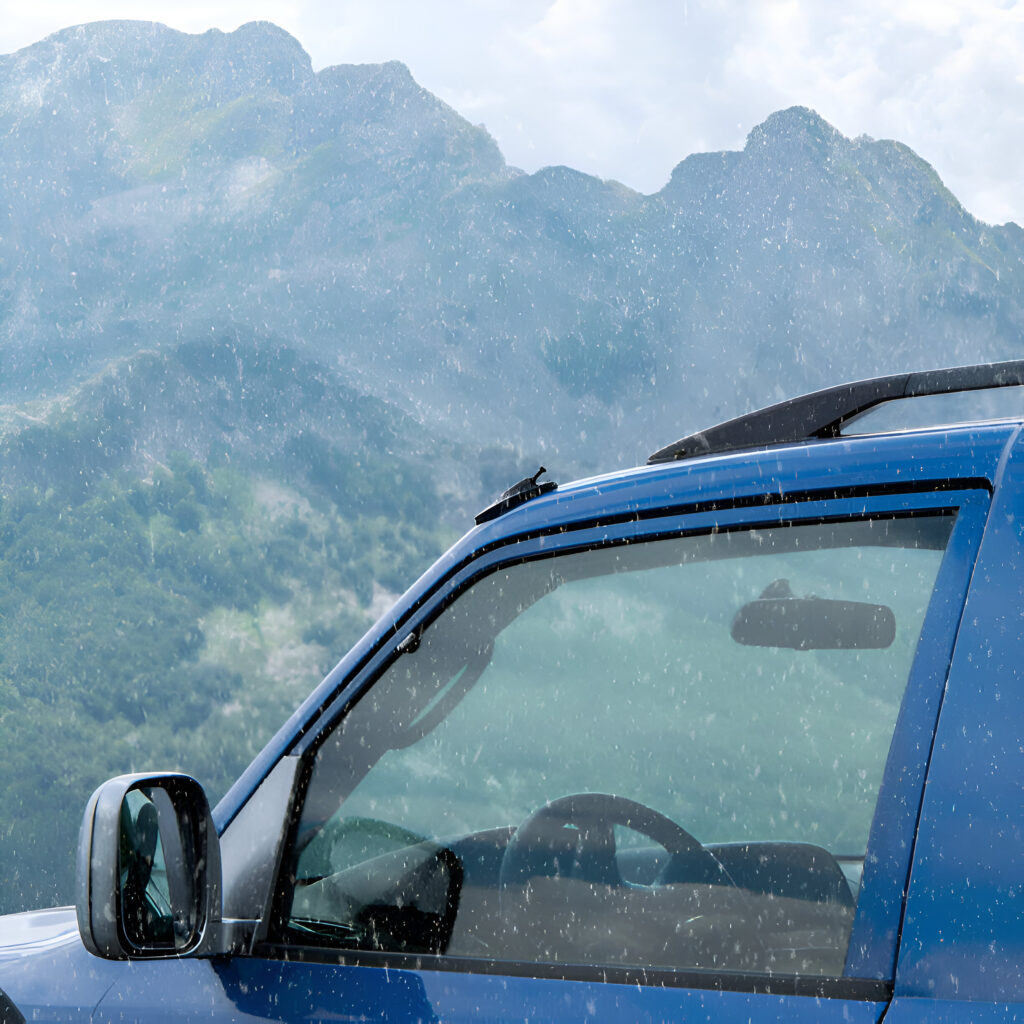 Winter in Albania: Best Mountain Drives 1 Blue car with roof rack parked in the rainy Albanian mountains, showcasing the scenic beauty of winter in Albania, ideal for planning a mountain drive with a reliable car rental.