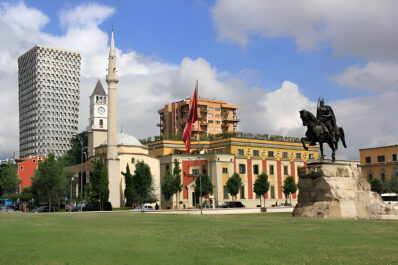 Skanderbeg Square in Tirana, Albania — a key starting point for the Tirana to Berat day trip, showcasing the National History Museum and iconic statue under blue skies.