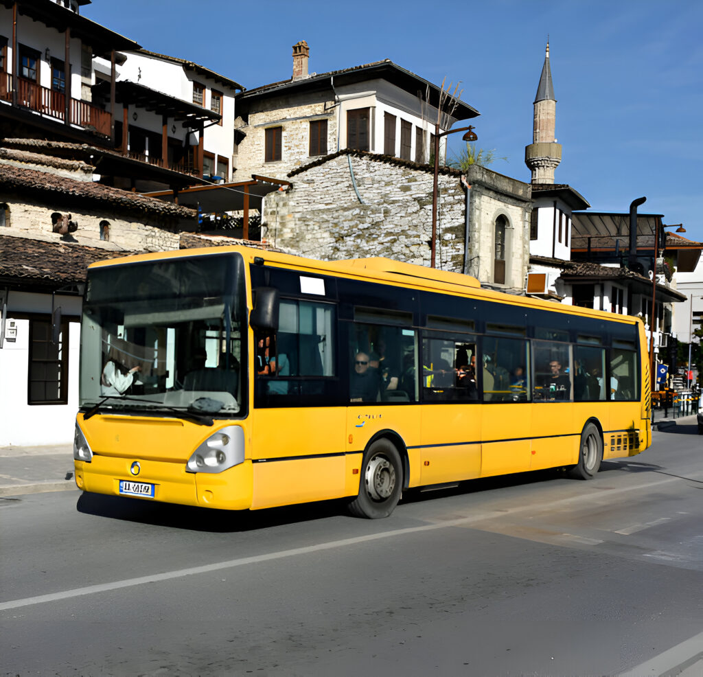 Yellow public transport bus in a historic Albanian town, showcasing affordable travel options. Ideal for comparing public transport vs. car rental costs in Albania on a budget to save money.